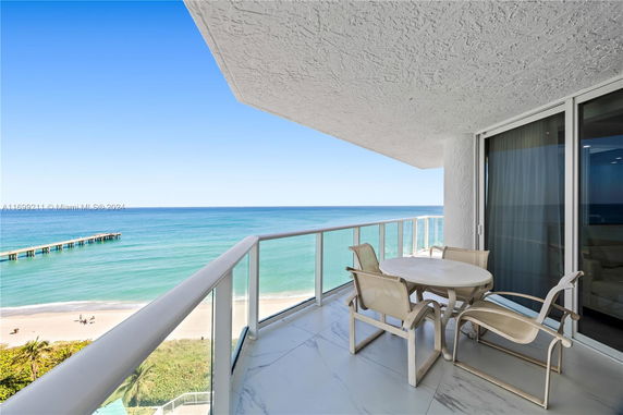 Balcony view overlooking the ocean with a round table and chairs.
