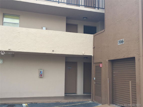Front view of a multi-story building with balconies and room entrances.