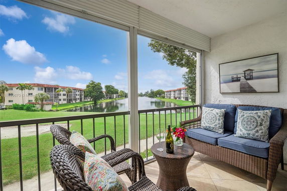 Panoramic view of apartments with a pond and greenery from a covered balcony.