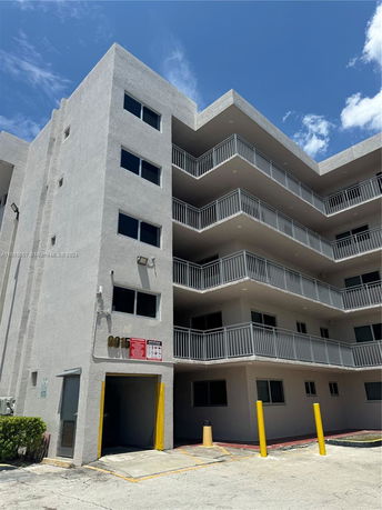 Front view of a multi-story building with balconies and a garage entrance.