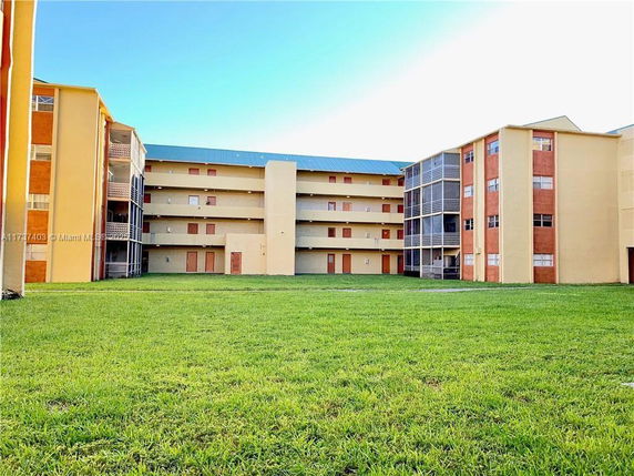View of a multi-story residential building with balconies and grassy courtyard.
