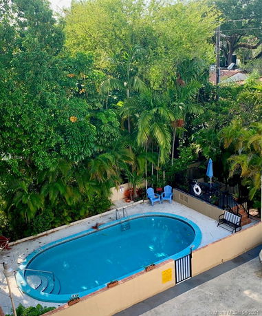 Outdoor swimming pool surrounded by lush greenery and seating area.
