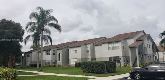 Front view of a two-story residential building with multiple units and a sloped roof.