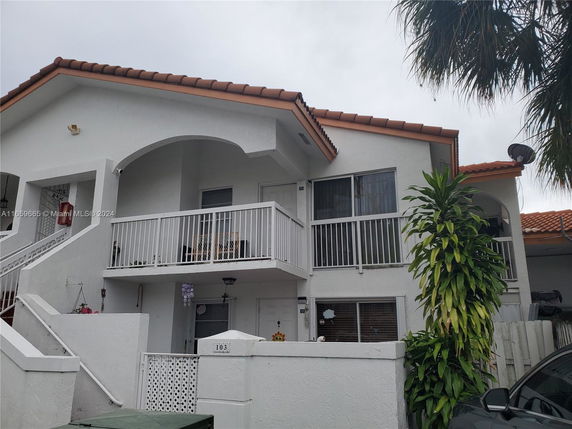 Front view of a two-story house with a balcony and red-tiled roof.