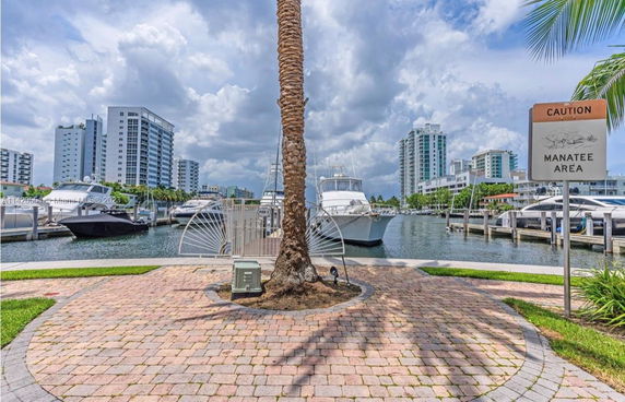 View of boats docked in a marina with tall buildings in the background.