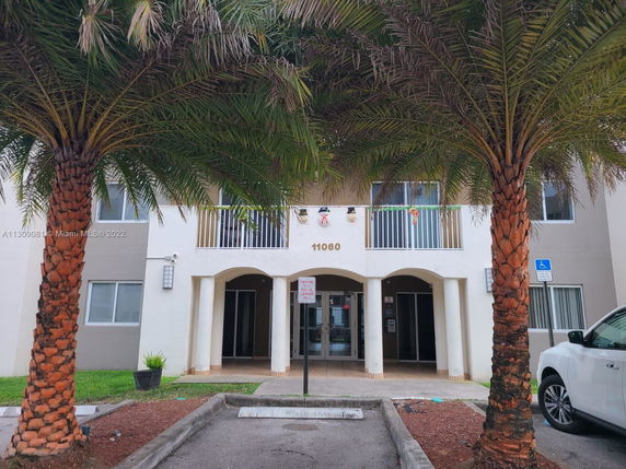 Front view of a multi-story residential building with balconies and an entrance porch.