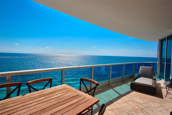 Balcony view overlooking the ocean under a clear blue sky.