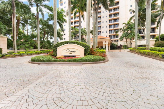 Front view of a multi-story building with a driveway and landscaped entrance.