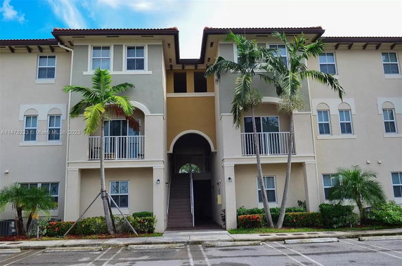 Front view of a multi-story residential building with balconies and a central staircase.