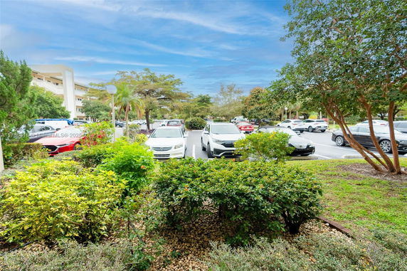 Outdoor parking area with multiple cars and surrounding greenery.