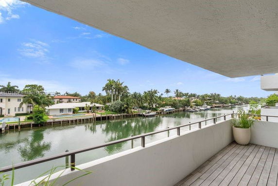 View from a balcony overlooking a canal with houses and palm trees.