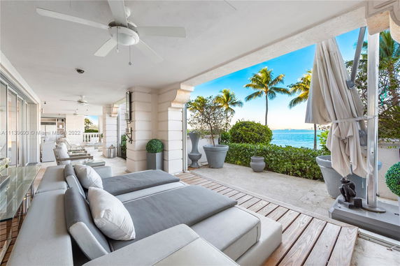 Outdoor patio area of a house overlooking a body of water with lush greenery and palm trees.