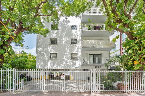 Front view of a multi-story residential building with balconies and gated entrance.