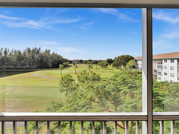 Panoramic view of a golf course and residential buildings from a window.