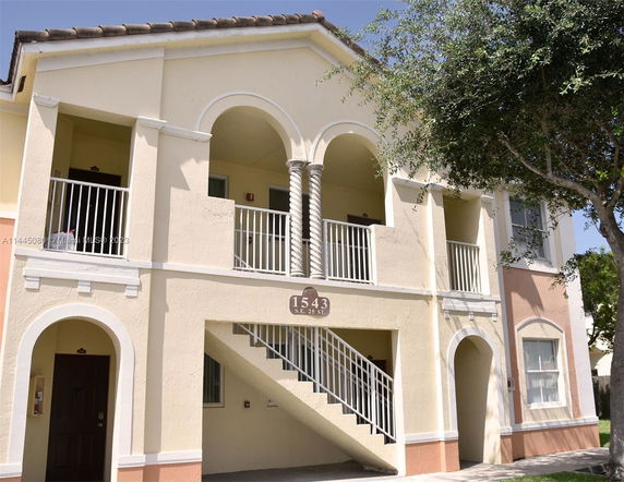 Front view of a multi-story residential building with staircases and balconies.