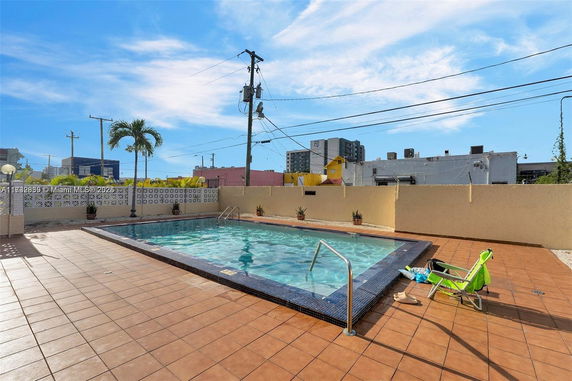 Outdoor swimming pool with tiled deck and surrounding buildings.