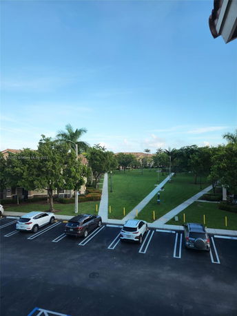View of a neatly organized outdoor parking area and a green space with pathways lined by trees.
