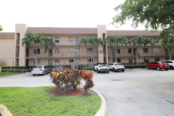 Front view of a three-story residential building with parking area.