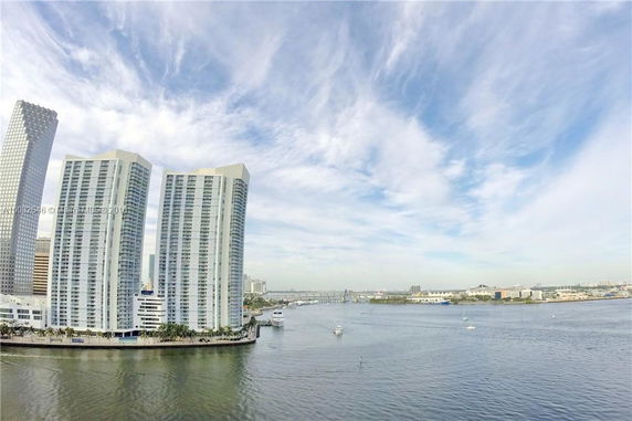Tall modern buildings overlooking a waterfront area with a clear sky.