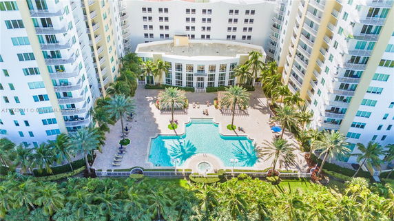 Aerial view of a building with a large outdoor swimming pool and surrounding recreational area.