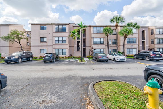Front view of a multi-story residential building with parking area.