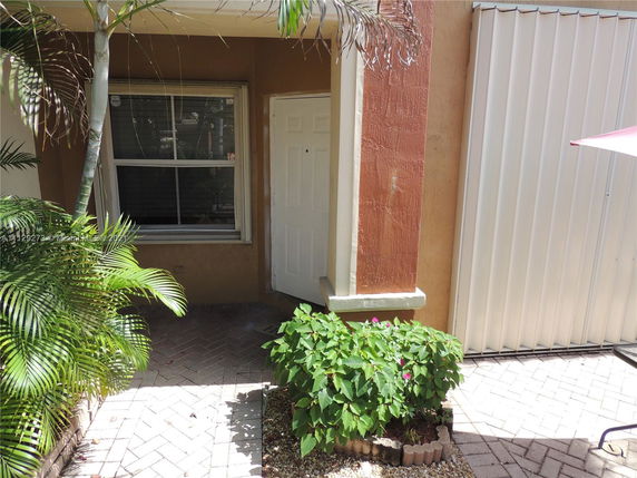 Entrance of a house with a small garden and window.
