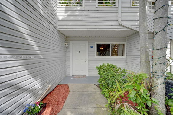 Front view of an apartment entryway with white siding.