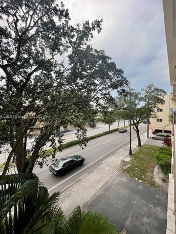 Street view from a building showing cars and trees along the road.