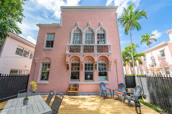 Front view of a pink two-story building with decorative windows and a wooden deck area.