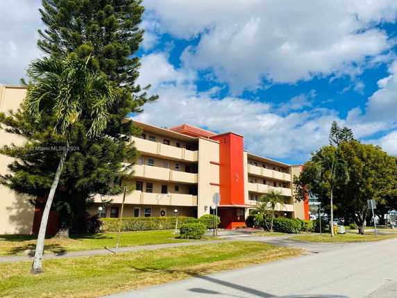 Front view of a multi-story residential building with red accents.