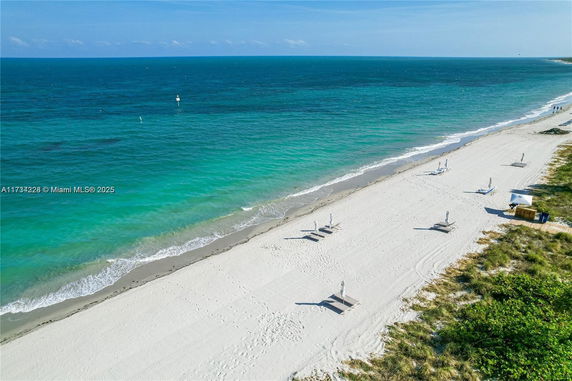Coastal view showing a sandy beach with turquoise ocean waters.