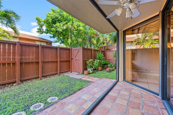 View of a fenced backyard area with potted plants and a sliding door.