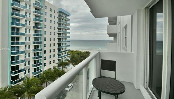 Balcony with a view of nearby apartment buildings and the ocean in the background.