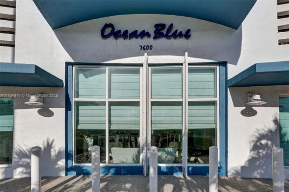 Front view of a modern building with large windows and a blue-colored awning.