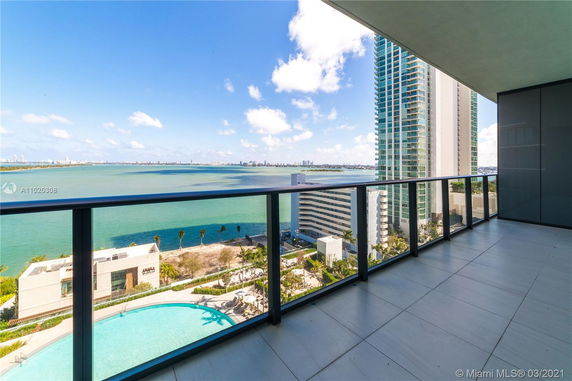 Panoramic view from a building balcony overlooking a city skyline and water body.