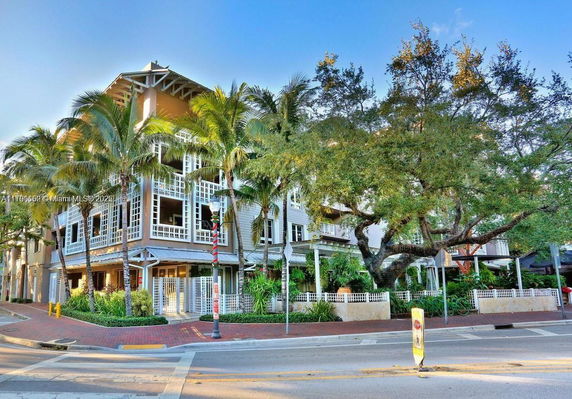 Front view of a multi-story building with large windows and palm trees.