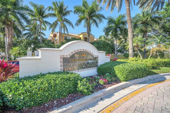 Front view of a luxury condominium with palm trees.