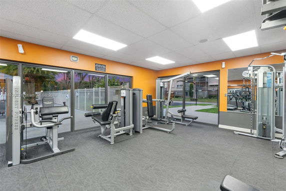 Interior view of a gym area with exercise equipment and large windows.