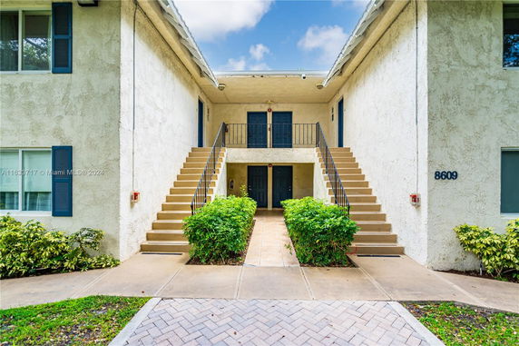 Front view of a two-story building with symmetrical exterior stairs and four doors.