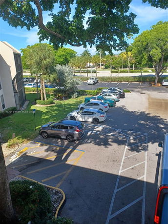 Outdoor parking lot with multiple cars and surrounding trees.