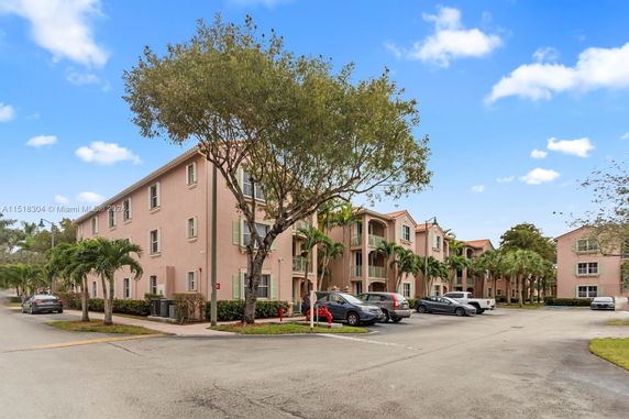 Front view of a multi-story residential building with balconies and palm trees.