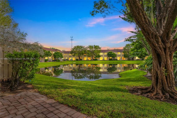 Scenic view of a housing complex with a pond and trees in the foreground.
