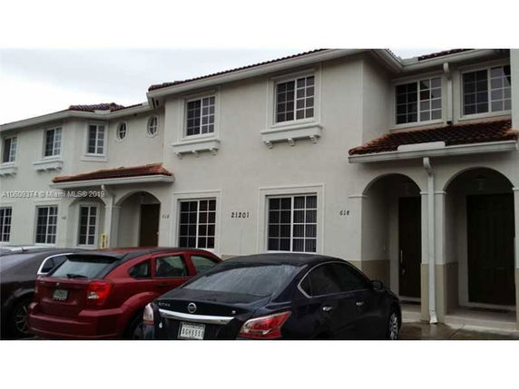 Front view of a two-story townhouse with cars parked in front.