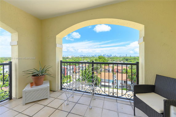 View from a balcony with outdoor seating overlooking a city skyline.