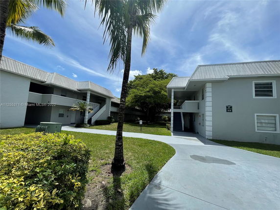 Front view of a two-story residential building with external stairs and metal roofing.