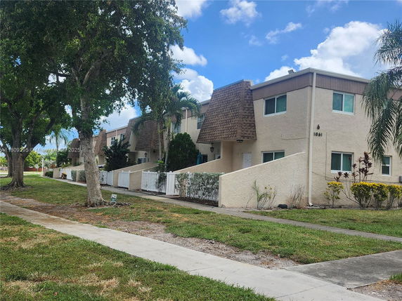 Front view of a two-story residential building with individual entrances and fenced patios.