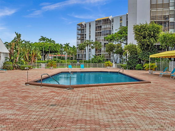 Outdoor pool area with surrounding apartment buildings and lush greenery.