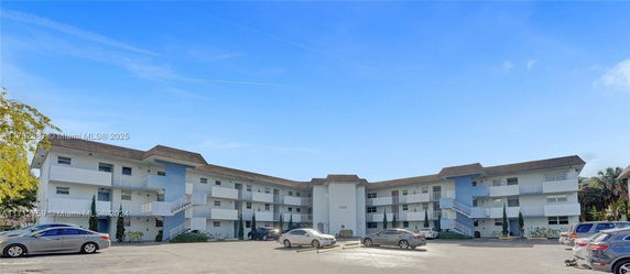 Front view of a three-story apartment building with a U-shaped design and exterior staircases.