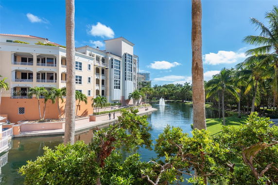 Exterior view of a multi-story building next to a water feature with palm trees around.