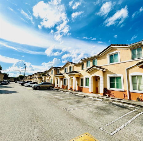 Front view of a row of two-story townhouses with parking spaces in front.